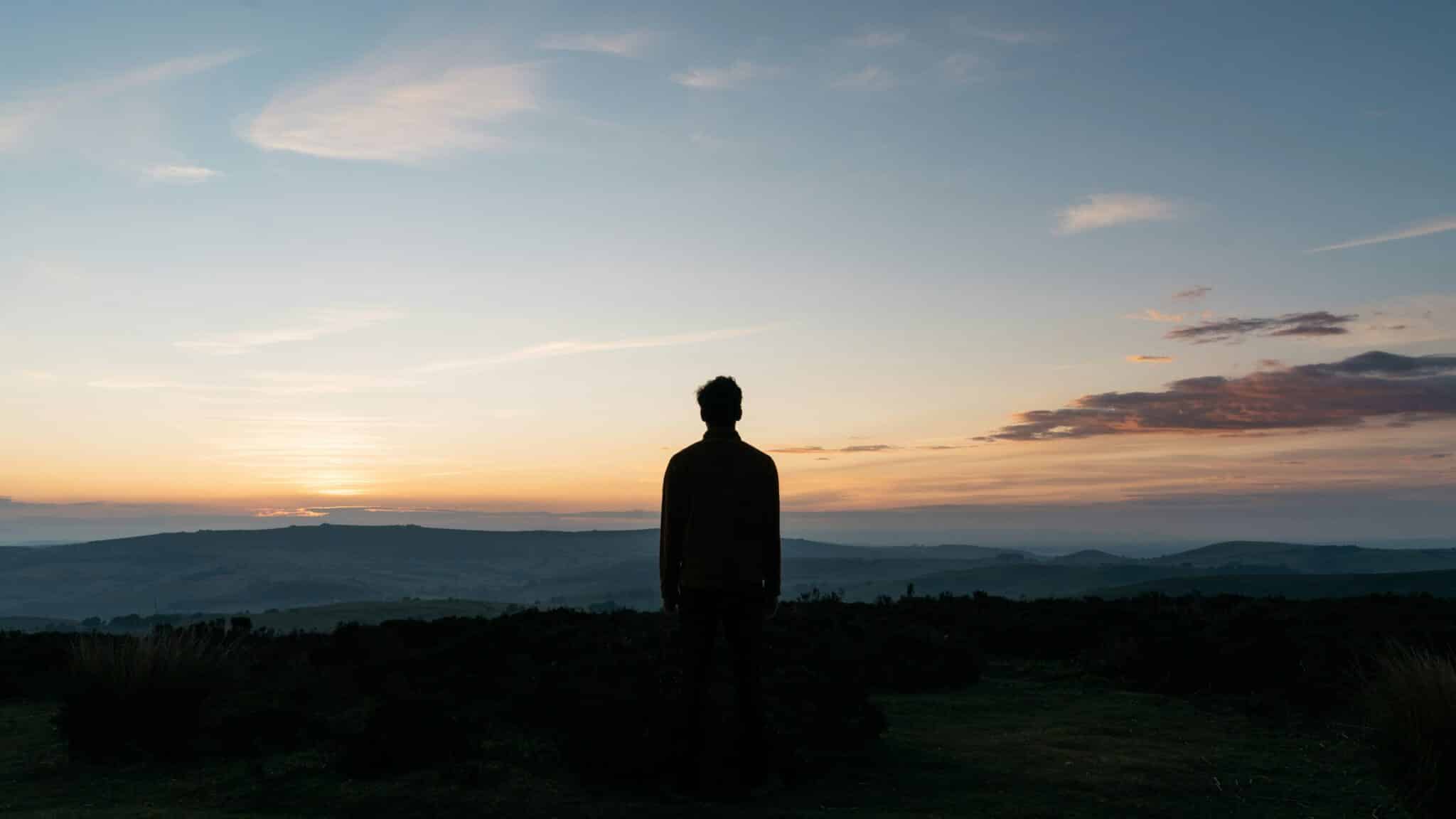 man looks at sunrise | Photo by Tom Allport on Unsplash