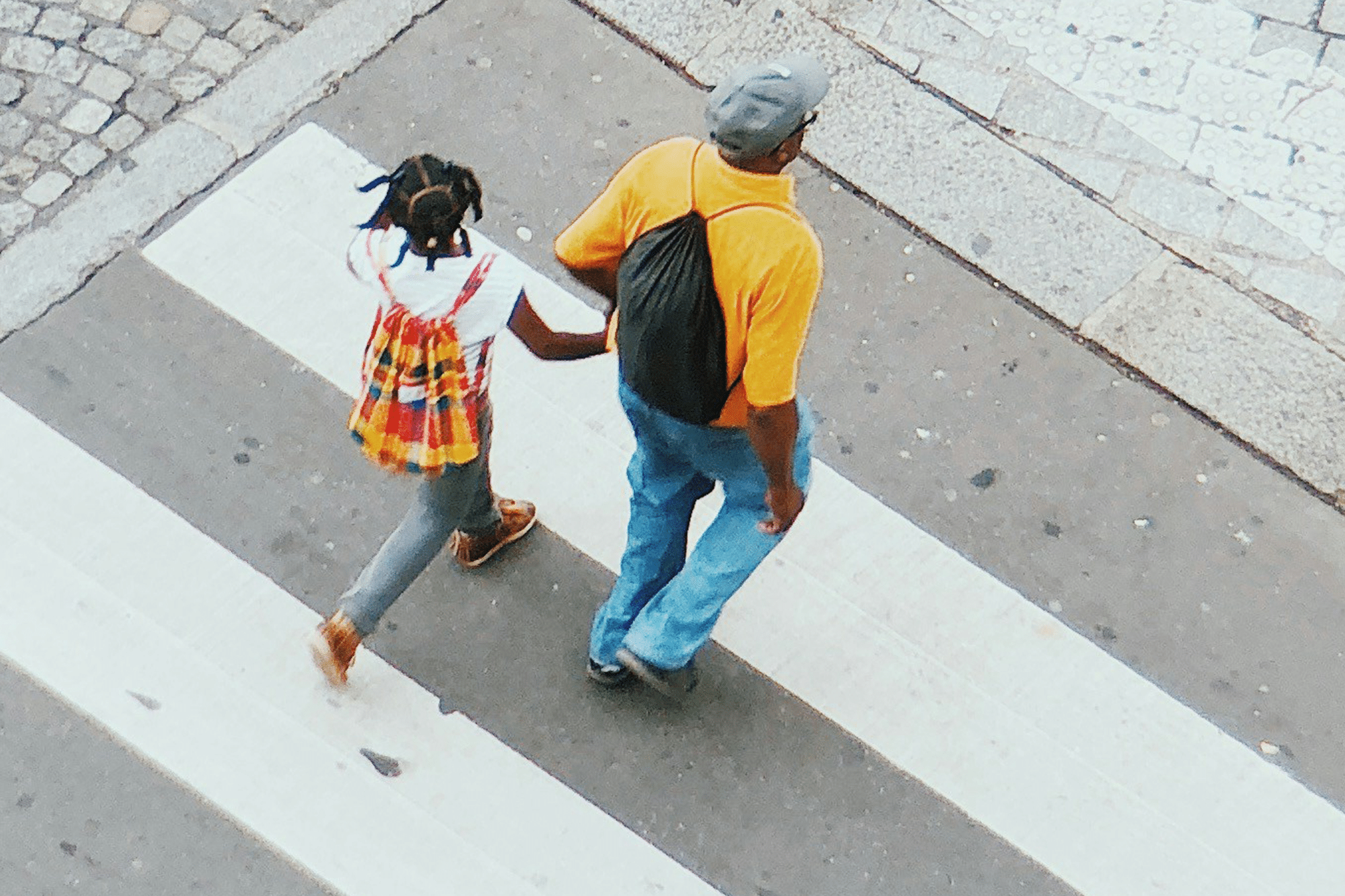 Father helps daughter cross the street.