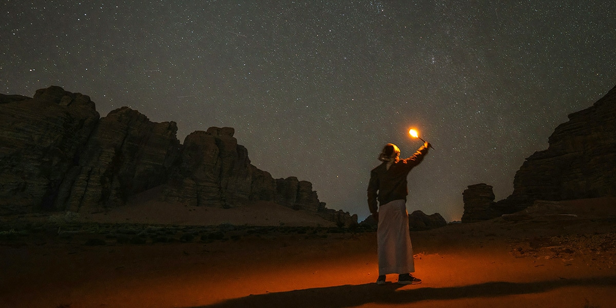 man in the dessert at night with a light.