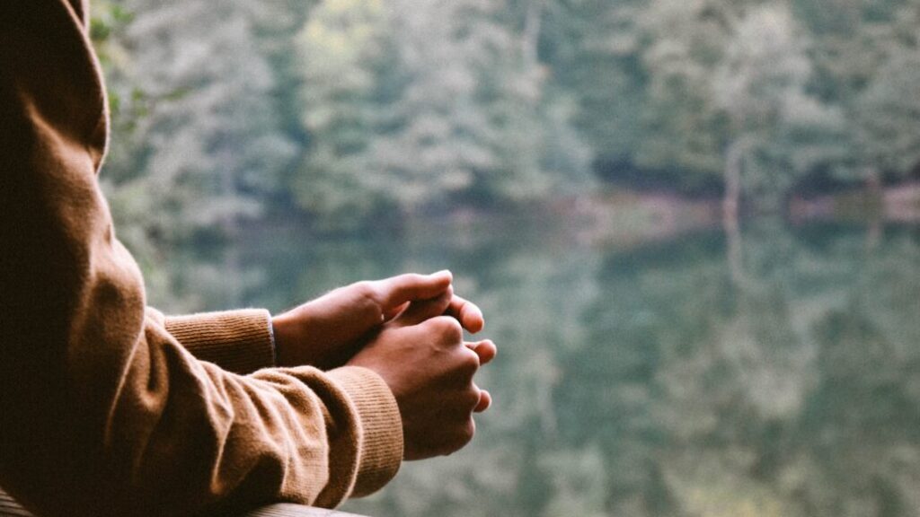 Man prays by a lake