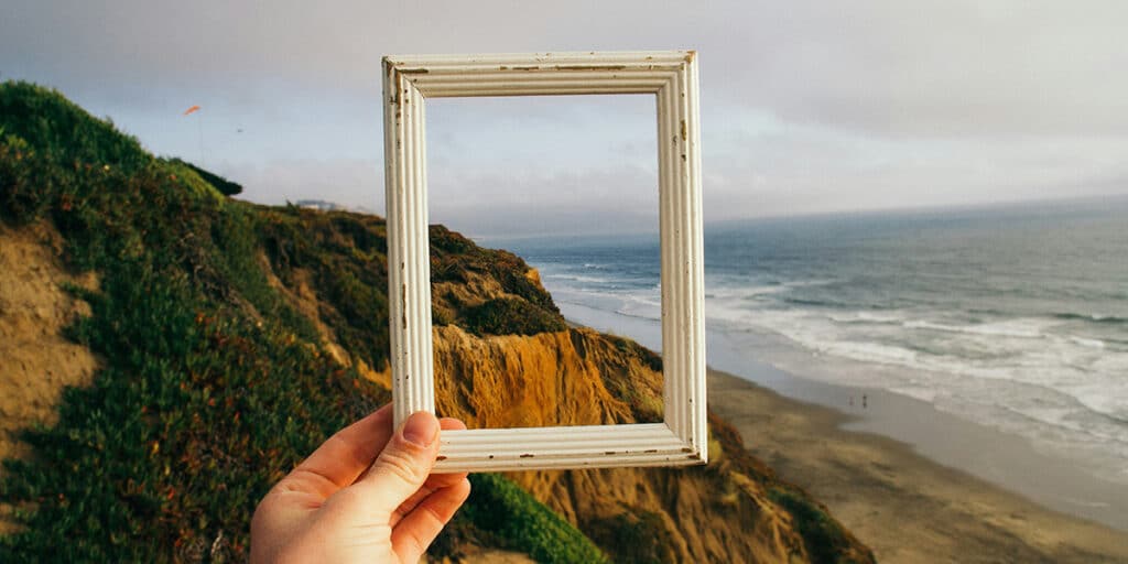 hand holding picture frame with landscape in background
