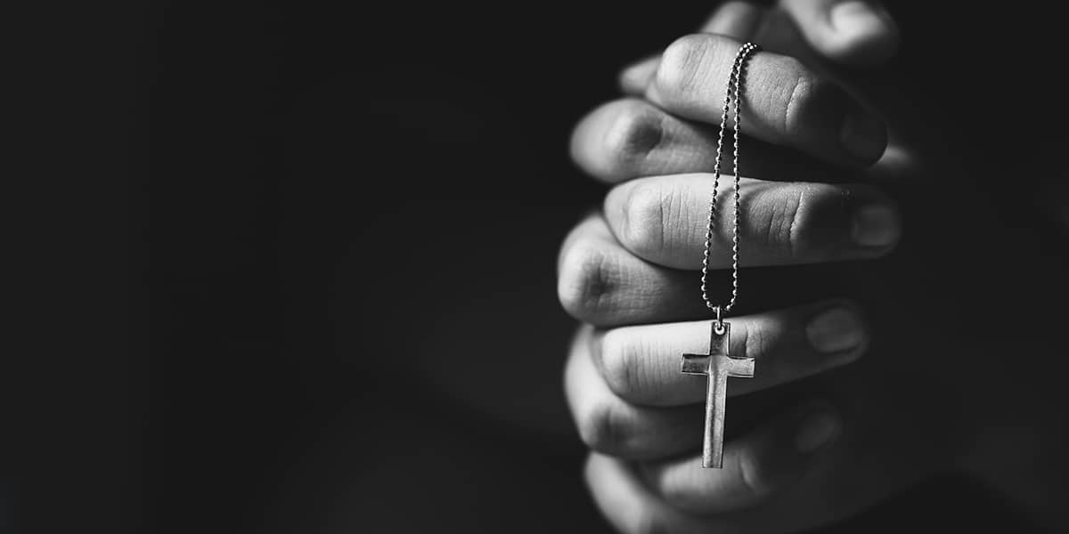 folded hands in prayer, holding a rosary