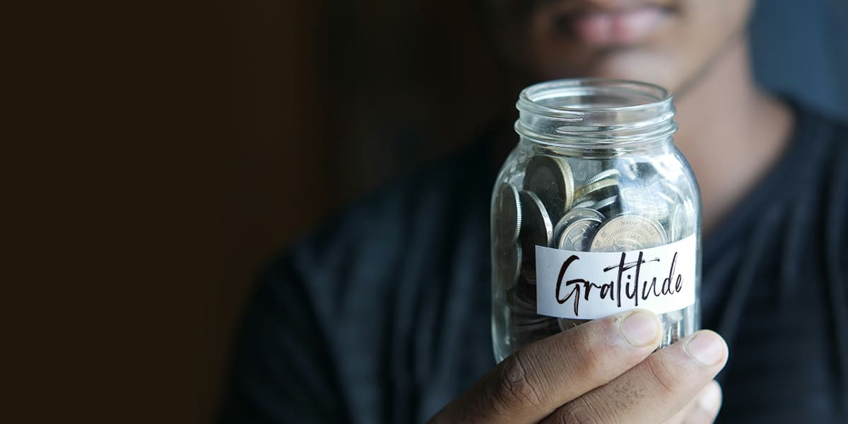 young man holding a gratitude jar full of money