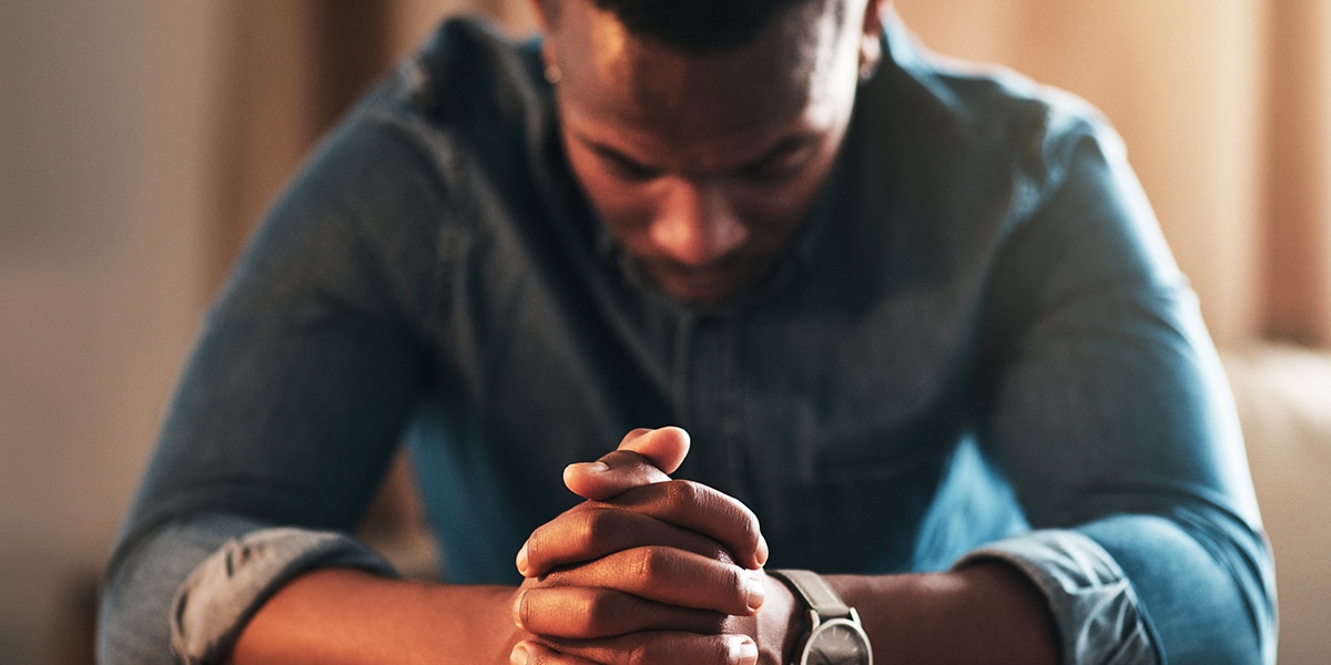 man with folded hands and bowed head praying