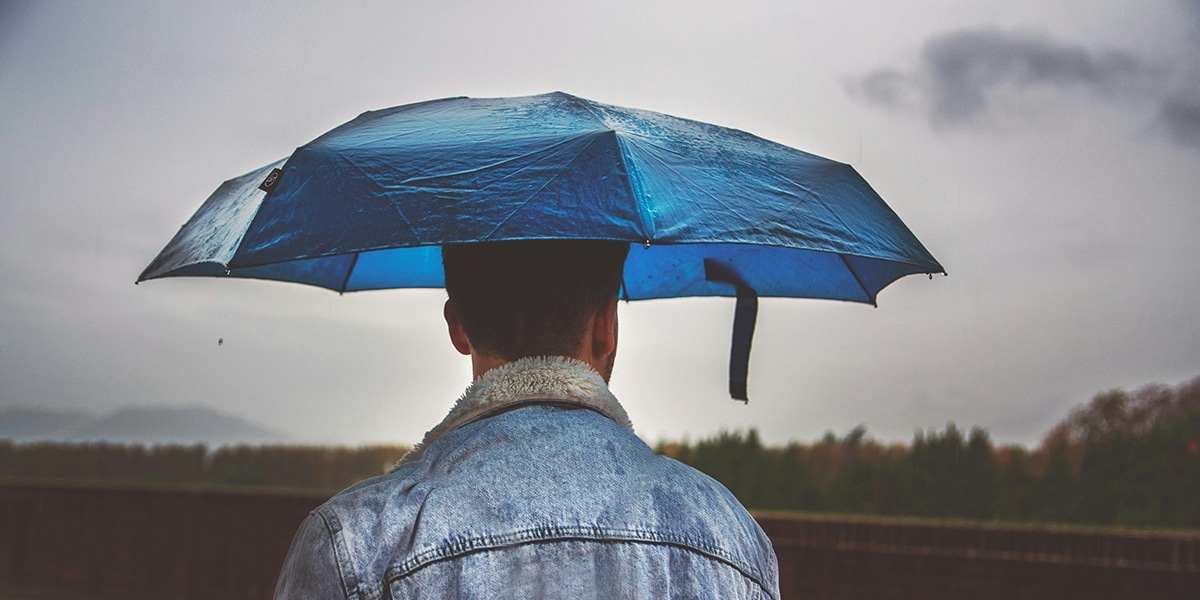 man holding blue umbrella to shield him from the rain
