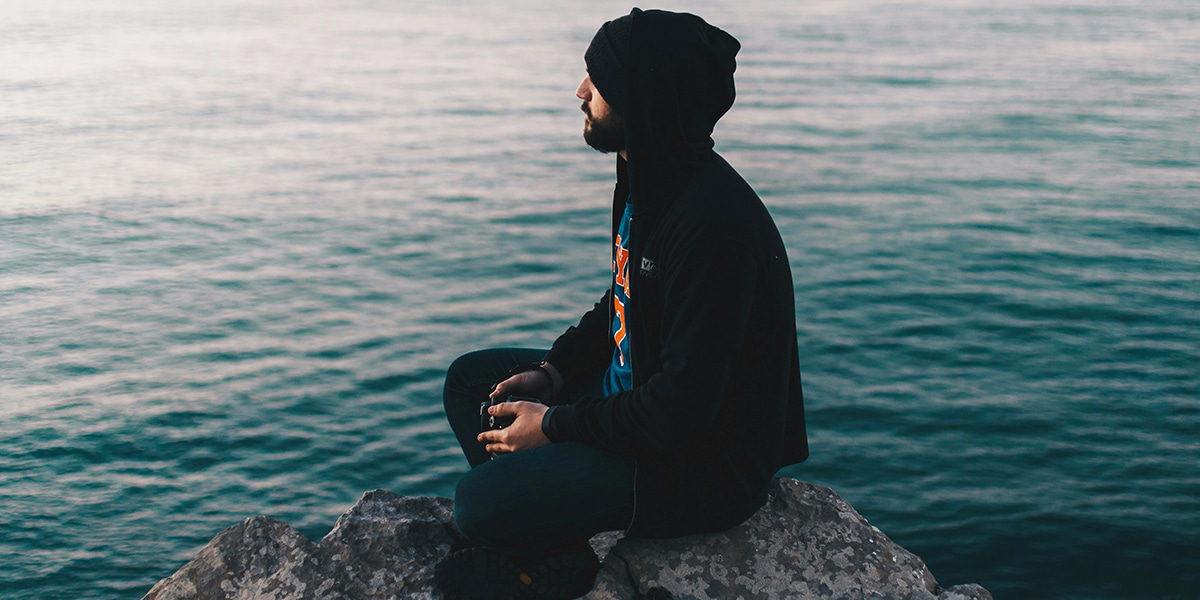 man sitting by the water reflecting