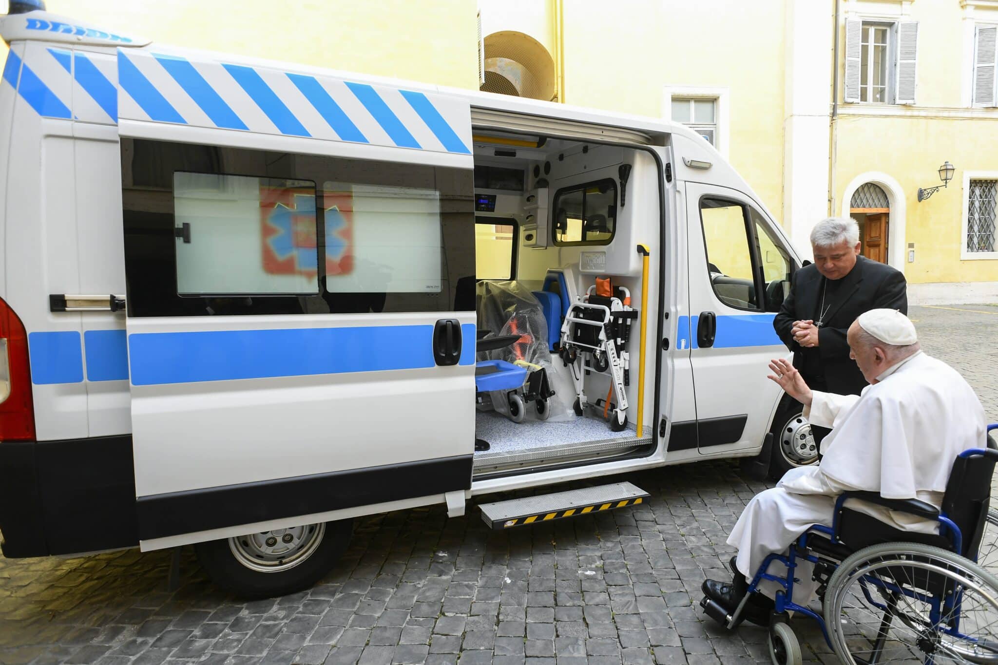 Pope Francis, alongside Papal Almoner Cardinal Konrad Krajewski, blesses an ambulance to be donated to a hospital in Ukraine's Ternopil region in this undated photo taken at the Vatican and released June 24, 2024.
