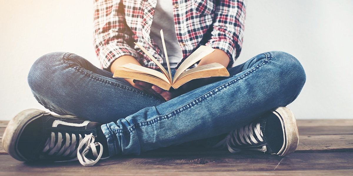 teenager reading the Bible while sitting on a wood floor