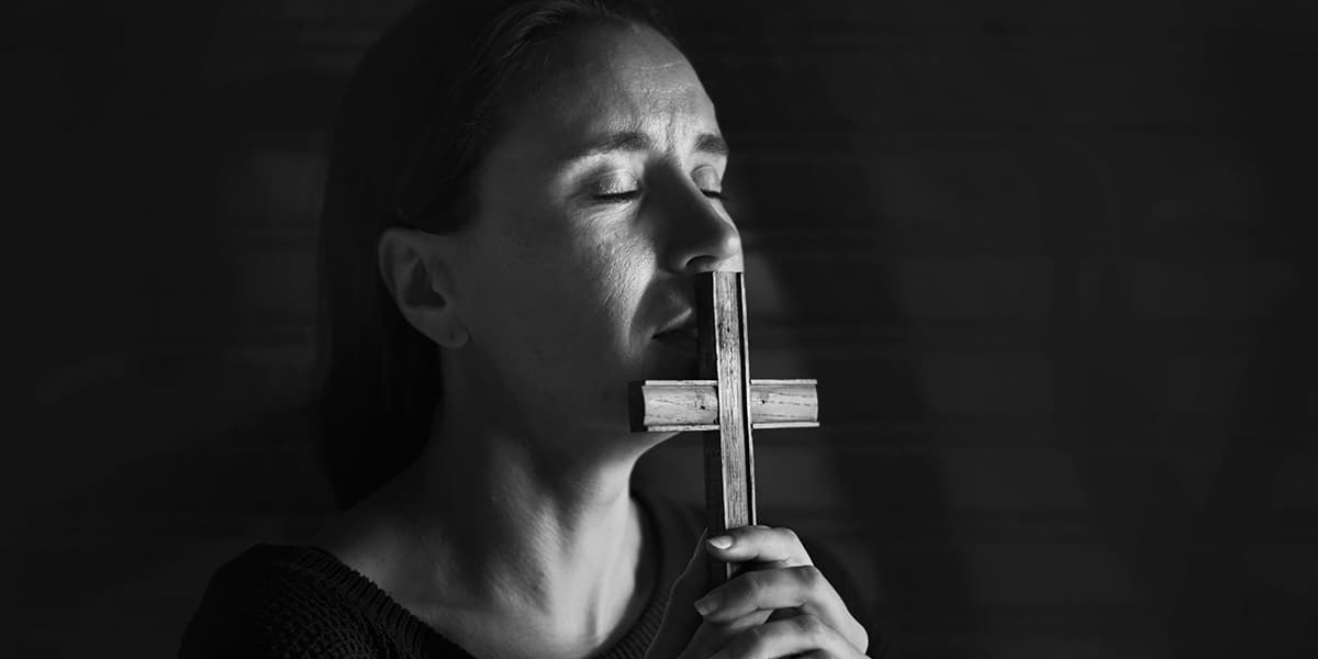 woman kissing a wooden cross