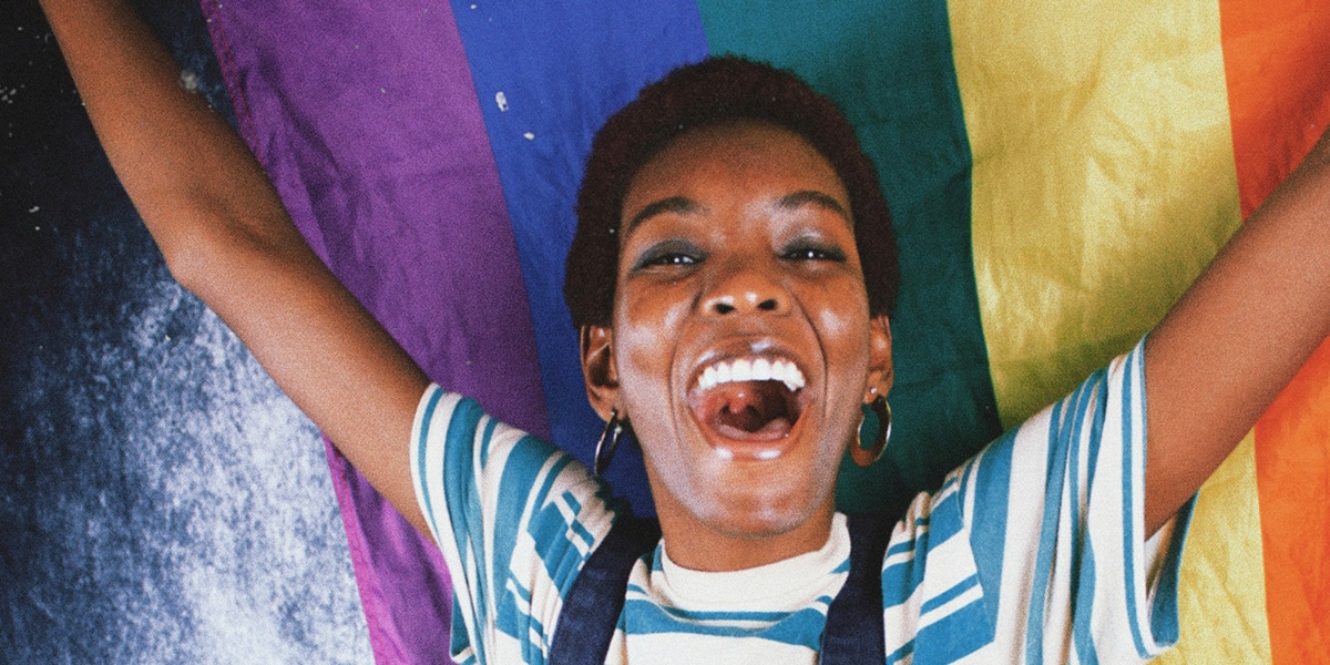 woman joyful, laughing while holding a rainbow flag