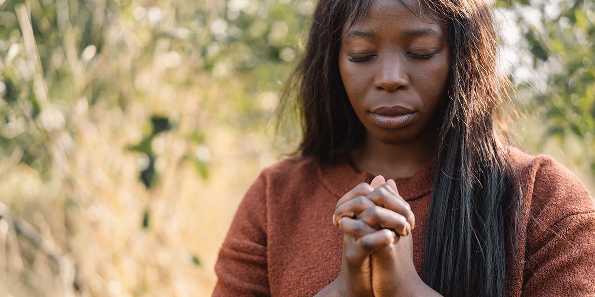 Woman praying with folded hands, outside