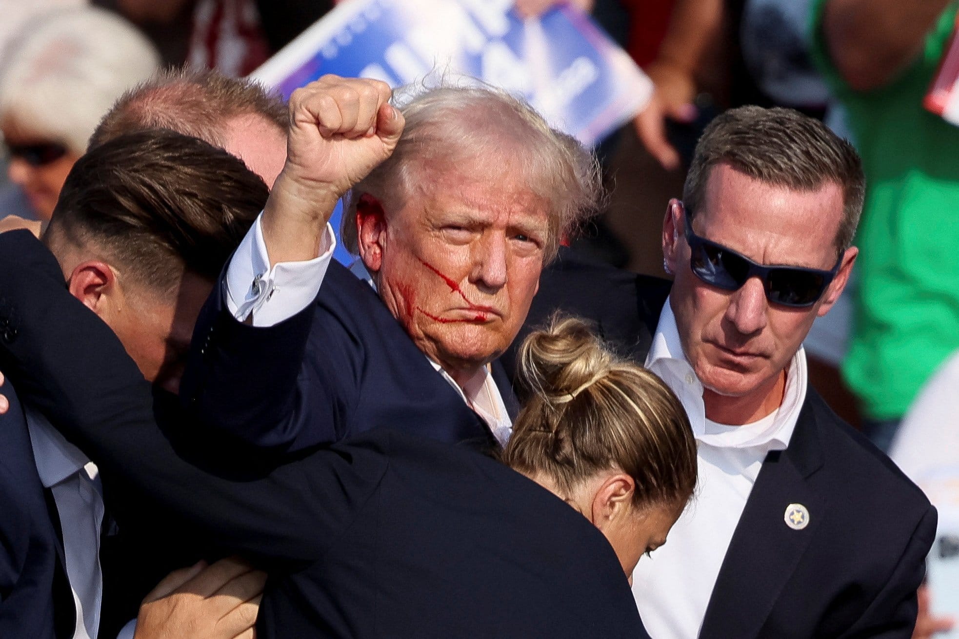 Republican presidential candidate and former U.S. President Donald Trump gestures, with blood on his face, is assisted by guards after shots were fired during a campaign rally at the Butler Farm Show in Butler, Pa., July 13, 2024. A local prosecutor says the suspected gunman and at least one attendee are dead. (OSV News photo/Brendan McDermid, Reuters)