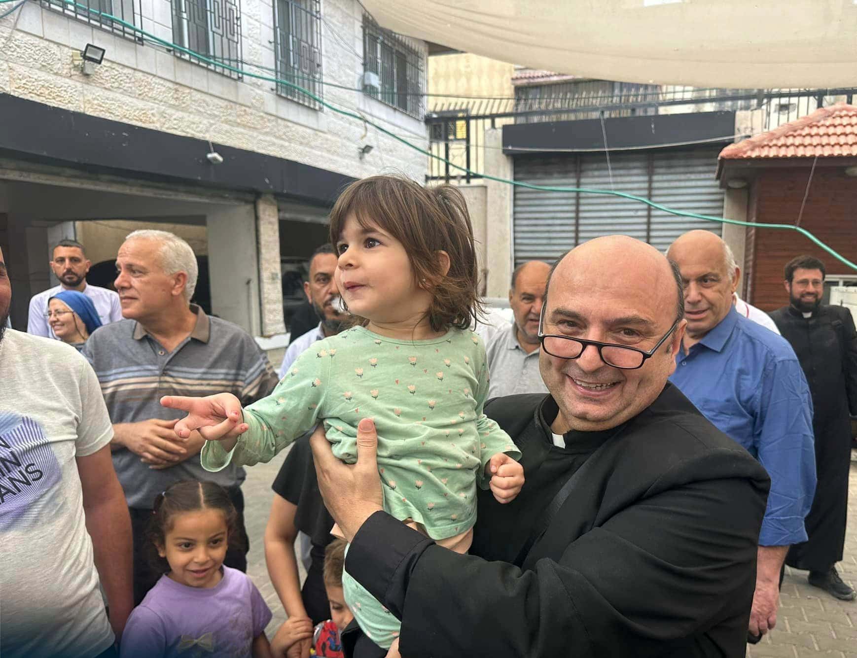 Father Gabriel Romanelli, Gaza City's Holy Family Parish priest, is seen with a parish child in Gaza City during the May 16-19, 2024, visit of the Latin patriarch of Jerusalem, Cardinal Pierbattista Pizzaballa. Father Romanelli returned to his parish community after he was stranded in Jerusalem after the Oct. 7, 2023, Hamas attack on Israel ad subsequent Israel-Hamas war that has left the northern Gaza Strip in ruins. He (OSV News photo/courtesy Latin Patriarchate of Jerusalem)