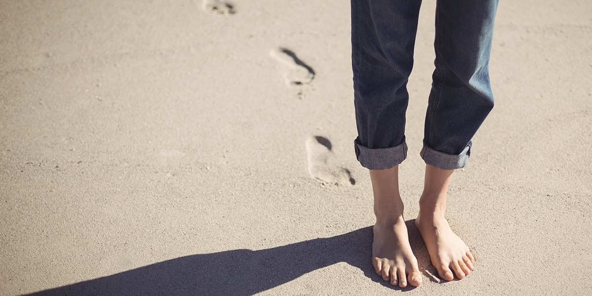 person walking in sand, leaving behind footprints