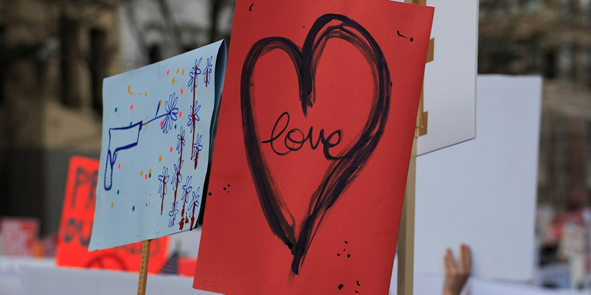 red sign with a heart and the word love during a rally