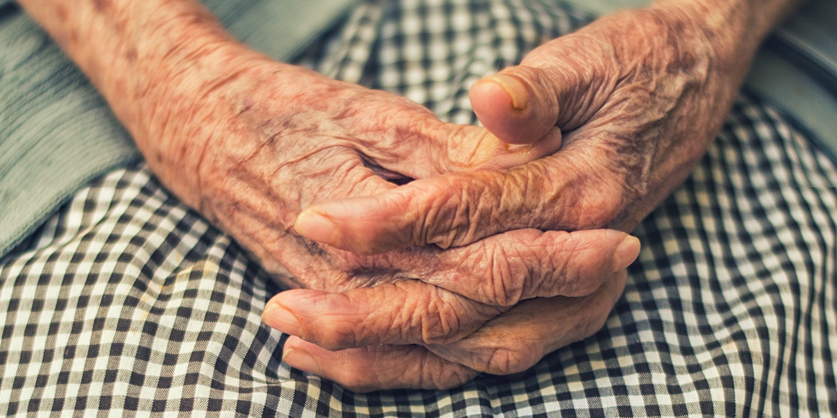 elderly woman with hands folded on lap.