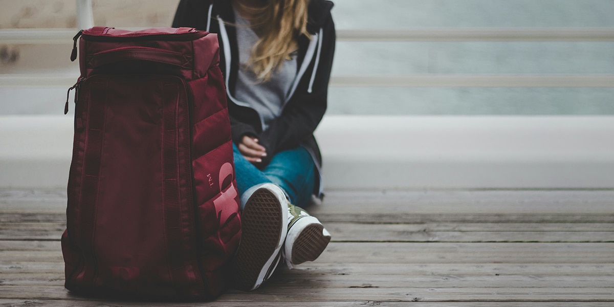 woman sitting on the ground next to her backpack with her belongings