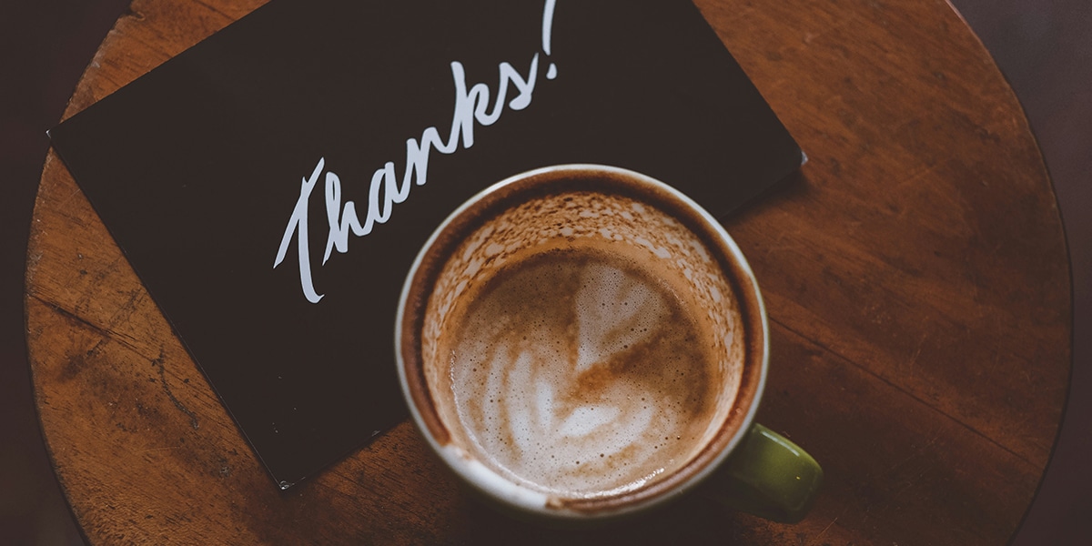 A thank you card and coffee on a table