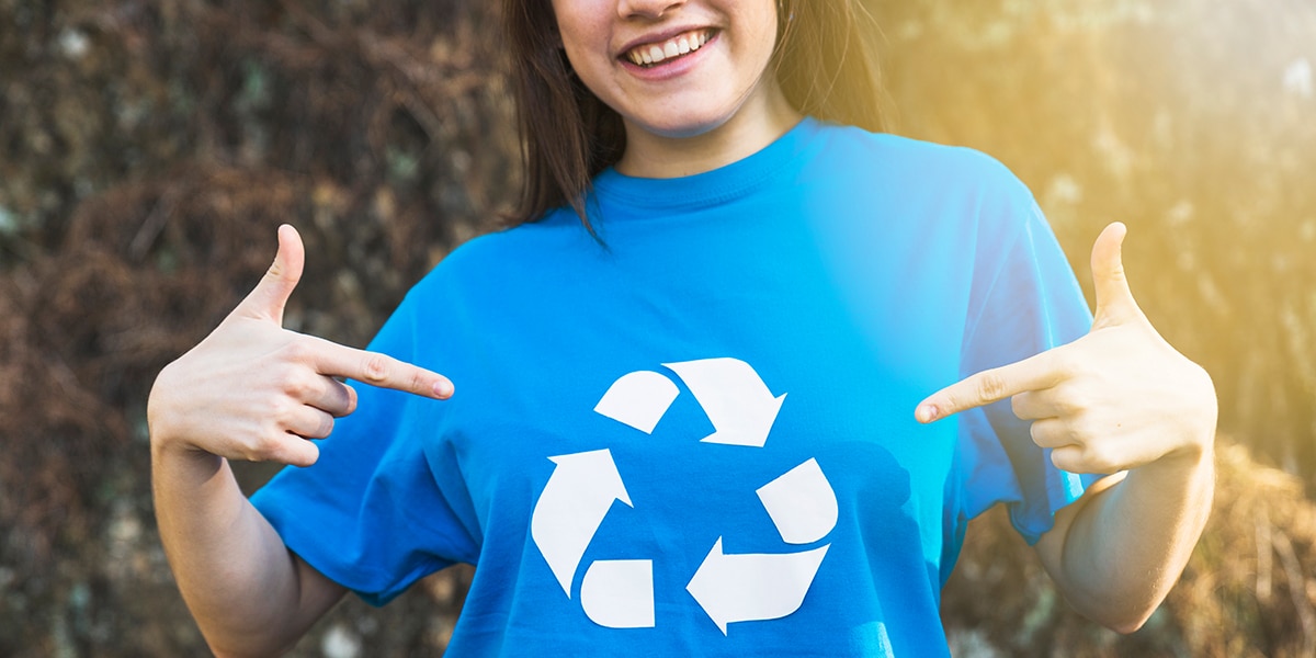 girl pointing at her t-shirt with the recycling logo