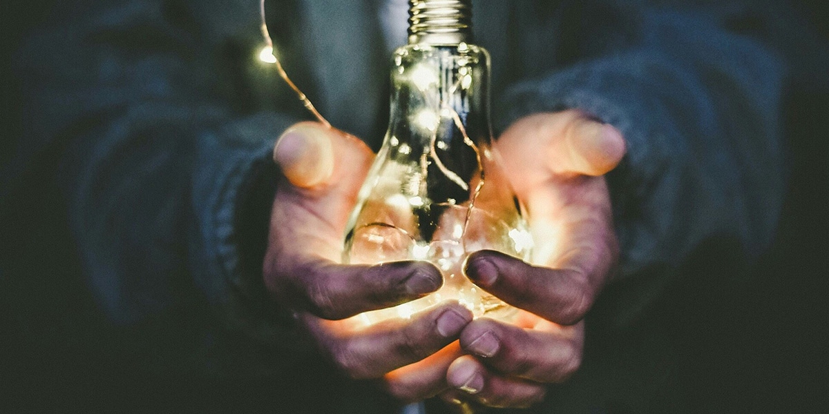 hands holding a glowing lightbulb