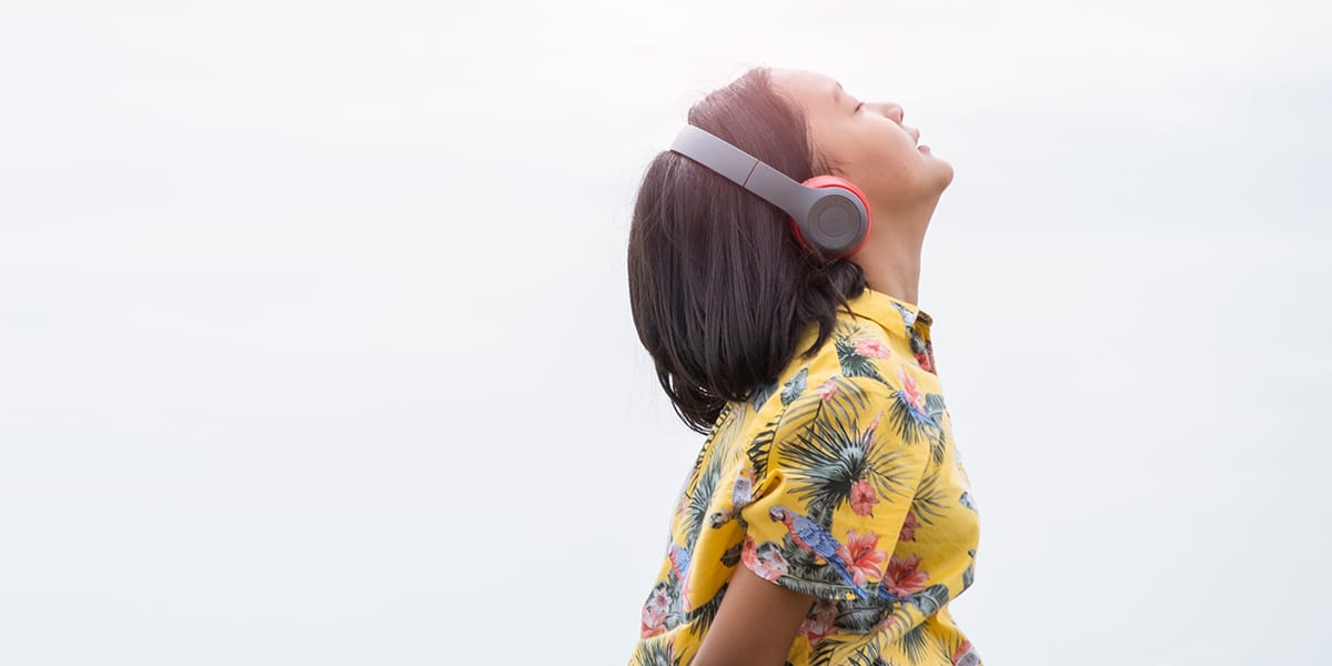 teen looking up to the sky while listening on her headphones