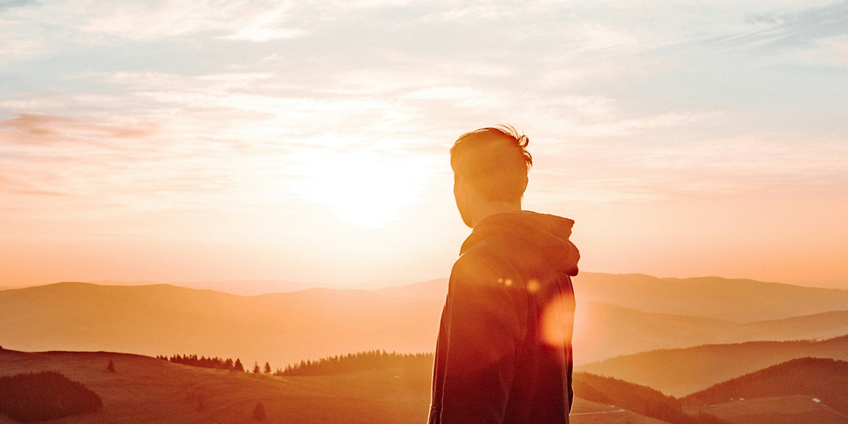 new day dawning, man watching the sunrise being bathed in sunlight