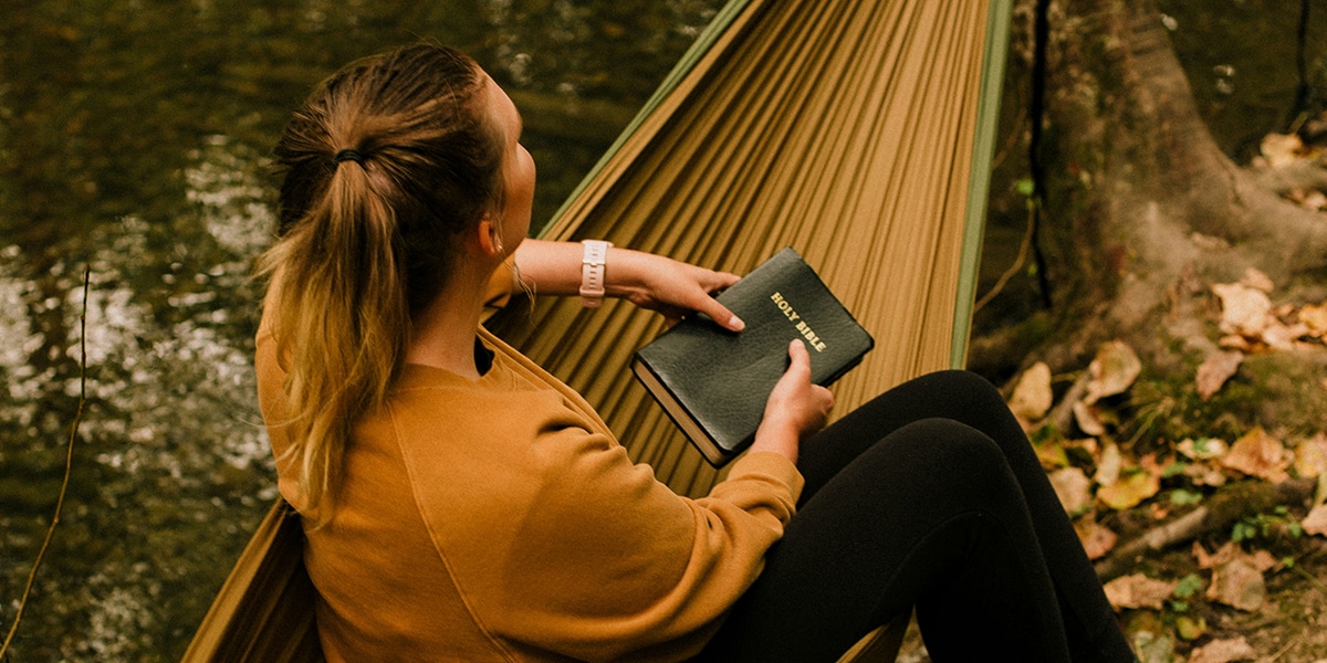 woman praying while holding her Bible