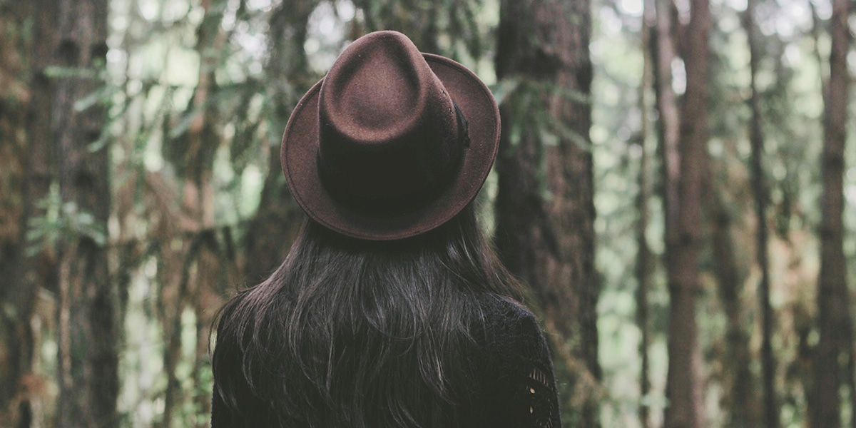 woman wearing a hat looking at a forest