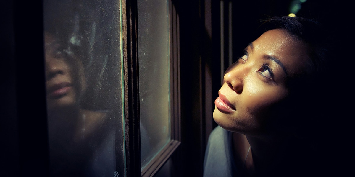 woman looking at stars through the window during the night.