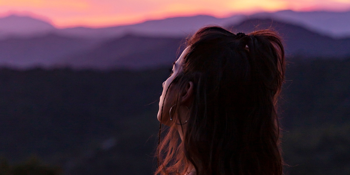 woman looking up at the horizon, watching a sunset