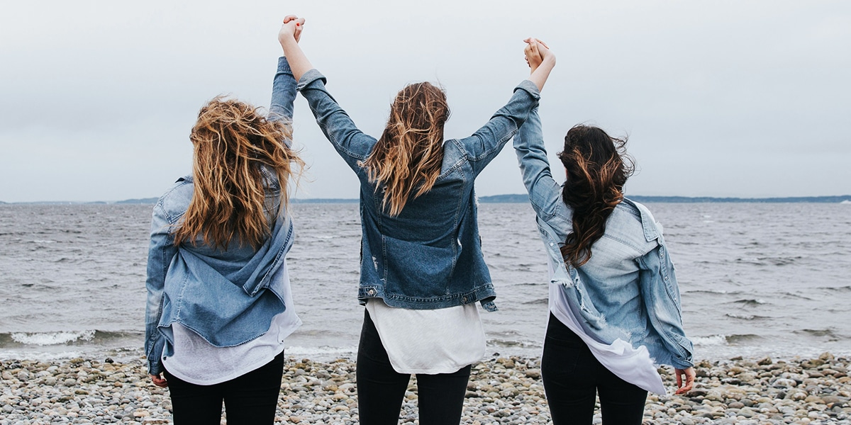 three women raising their arms in victory and celebration