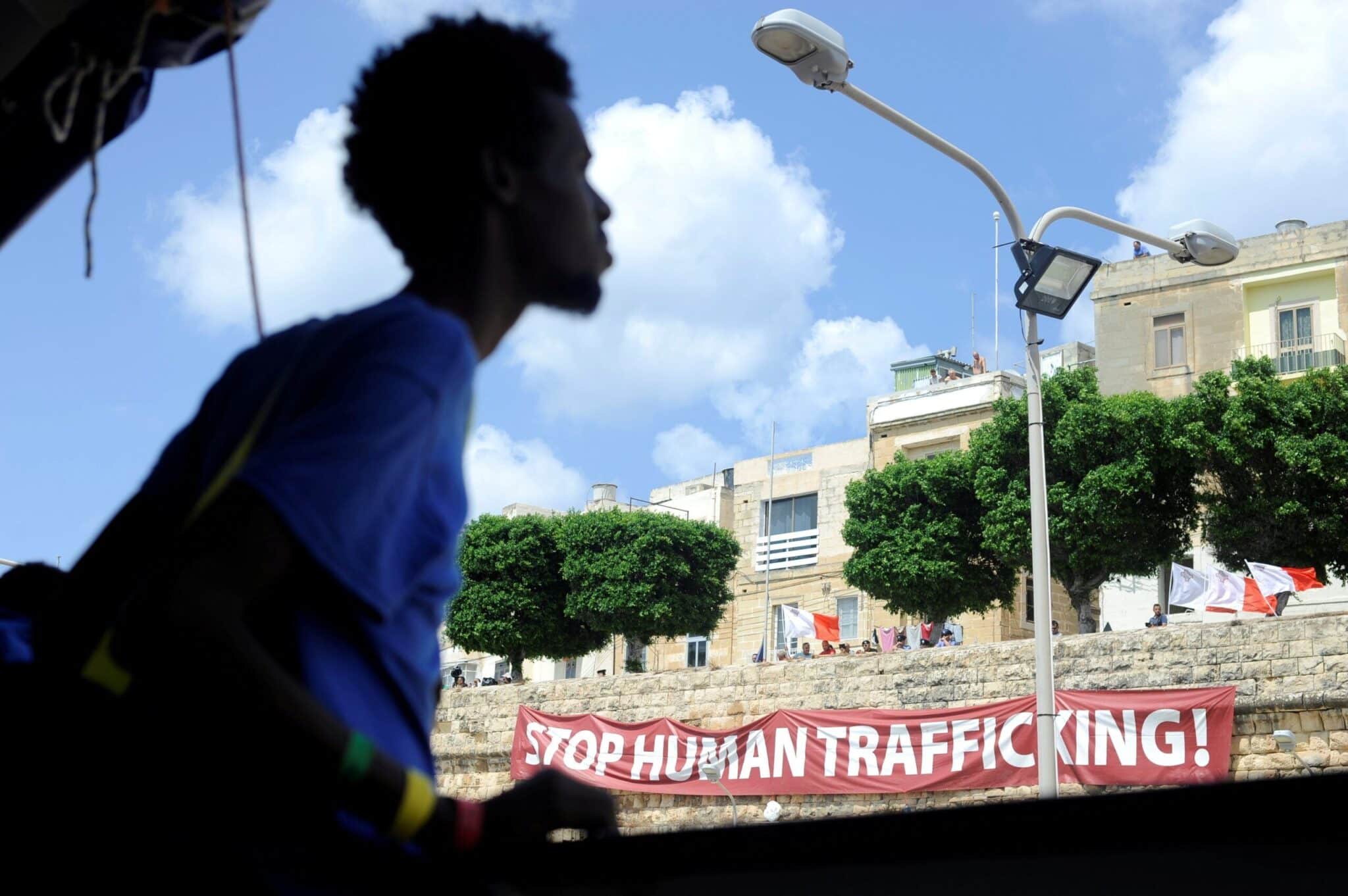 A man walks past a banner reading "Stop Human Trafficking!" in 2018 in Valletta, Malta. (OSV News photo/Guglielmo Mangiapane, Reuters)