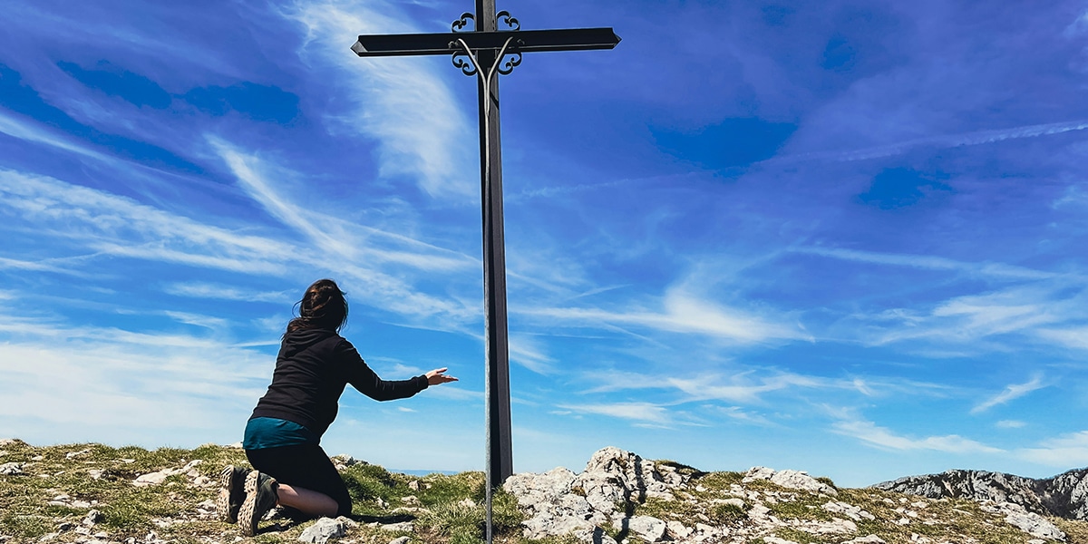 woman kneeling before a cross