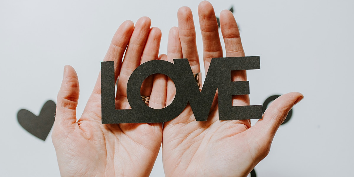 hands holding cut out paper letters spelling the word love.