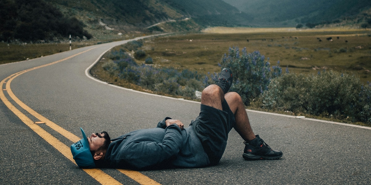 man laying down on road, looking up to the sky.