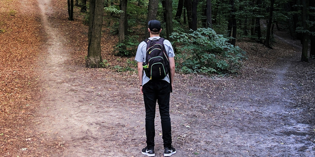 A young man deciding on which of two paths to take.