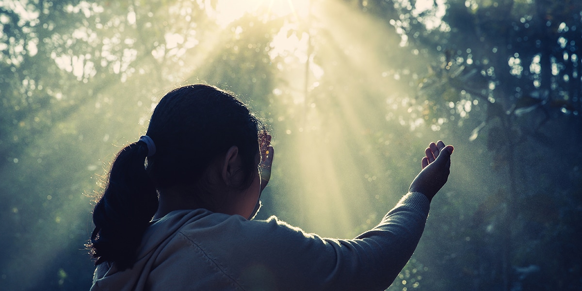 sunlight is reflecting on a woman while she is praying