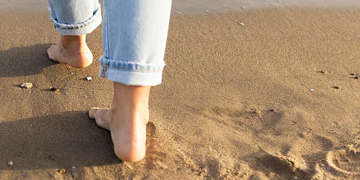 feet walking on sand, leaving footprints behind