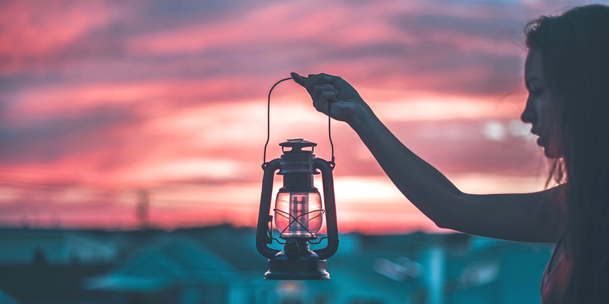 woman holding a lantern at sunset