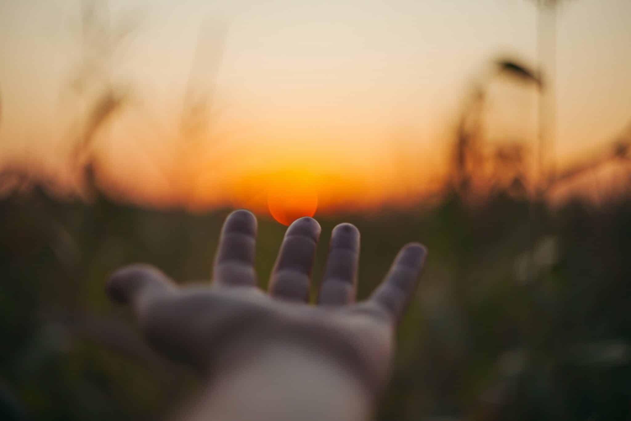 open hand ready to receive with a sunset in the background