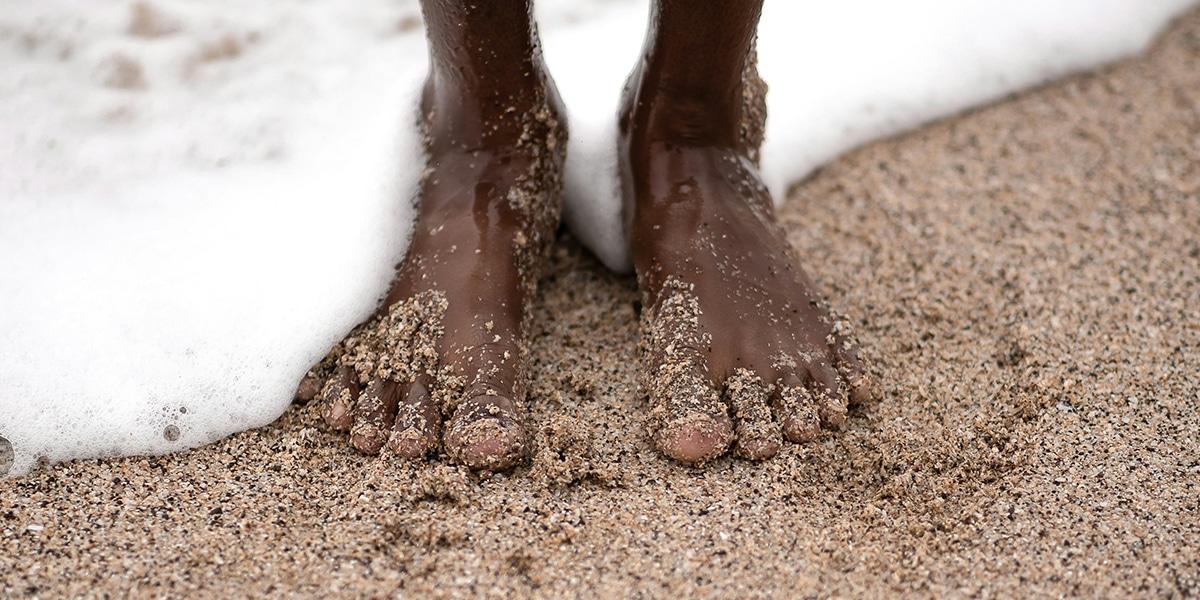 feet surrounded by ocean water and sand