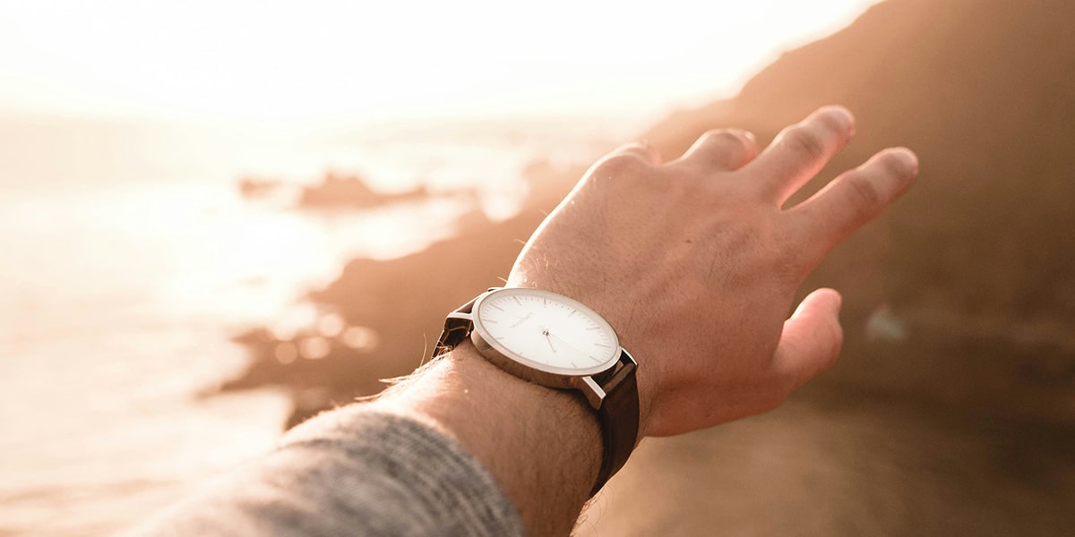 hand with watch, showing time with sunshine in the background