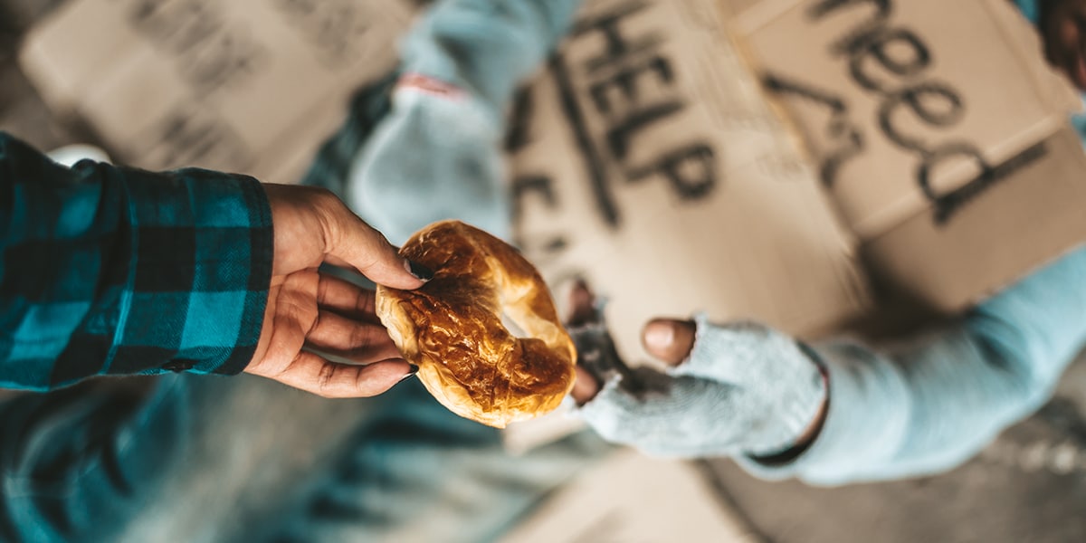 person giving food to a homeless person