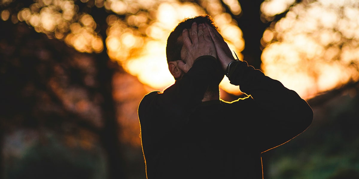 man in anguish and sorrow putting his hands in front of his face