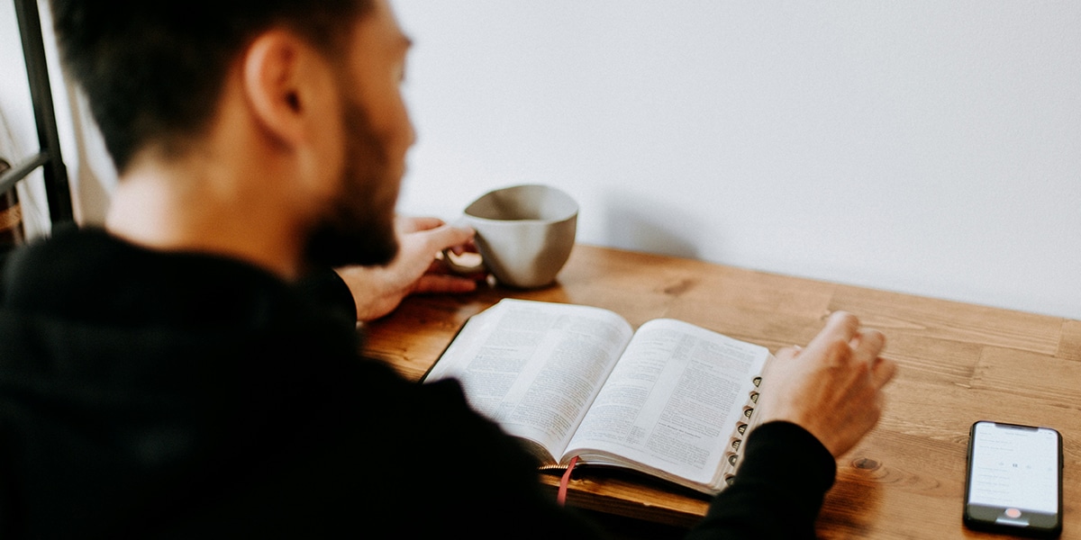 man sitting at a table reading his Bible