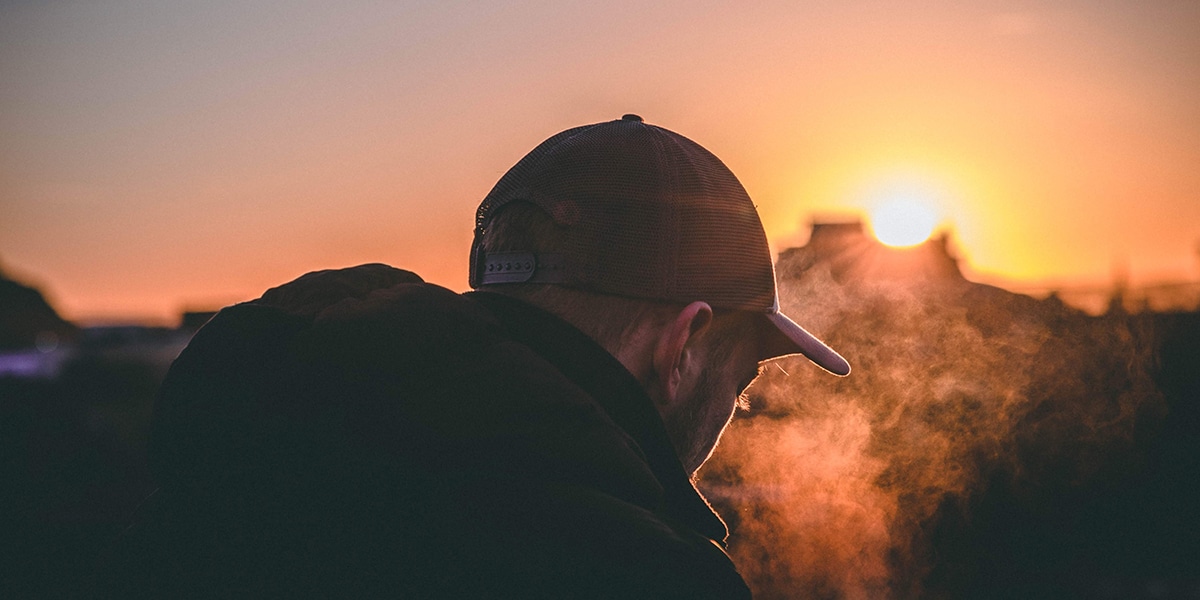 sad man sitting outside during a sunrise