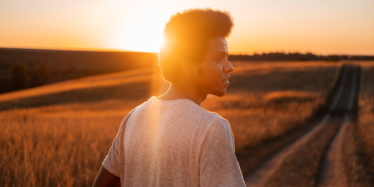 sunlight reflecting on a man walking down a field