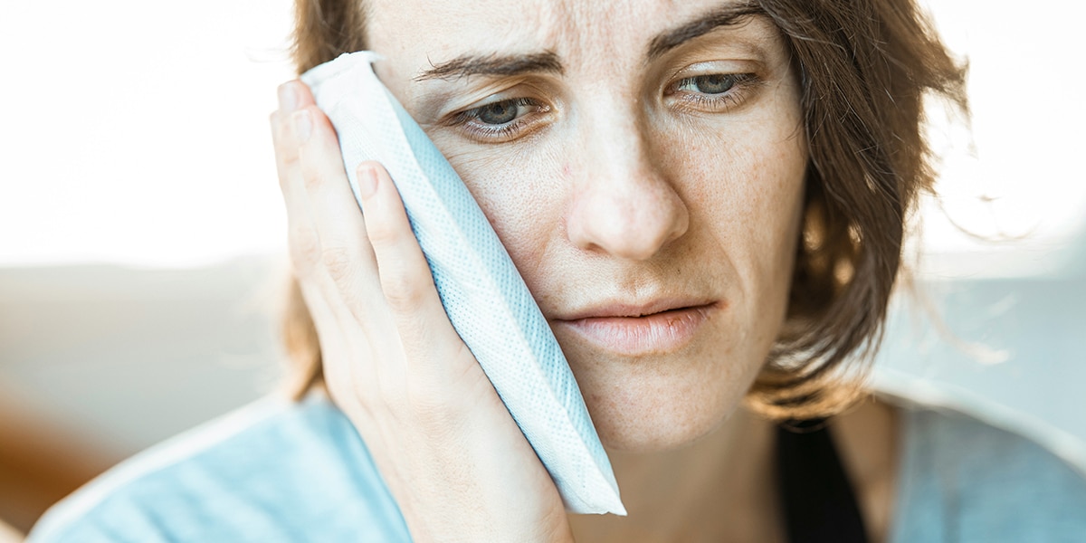 woman holding a icepack agains her painful head.