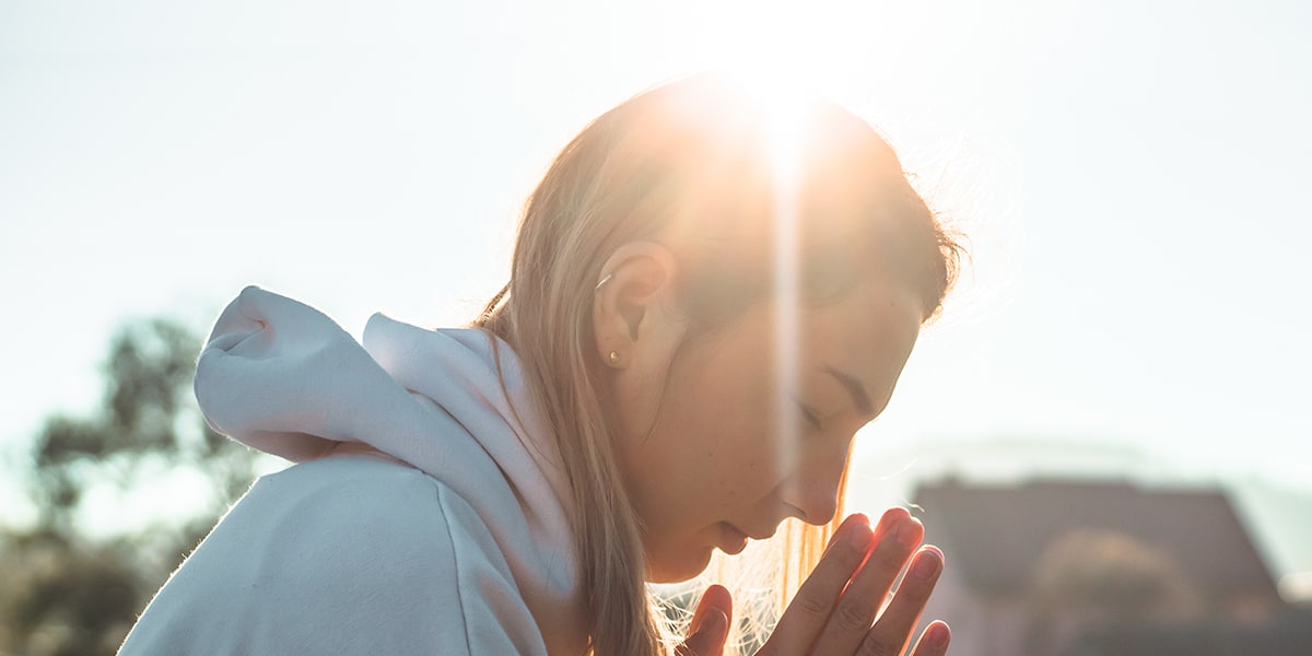 Light reflecting on a woman's head during prayer