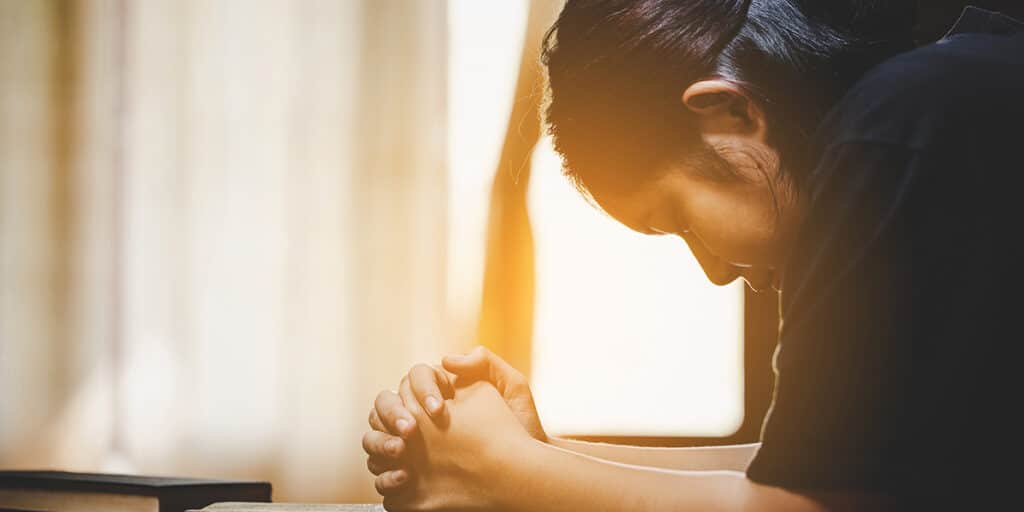 young woman praying with folded hands